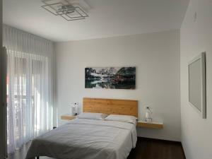 a white bedroom with a bed and a window at Nest & Relax in Trento
