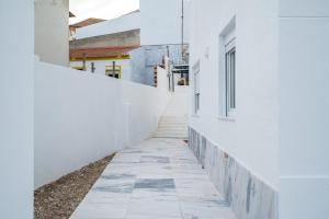a corridor of white buildings with a white wall at Almada Cityscape Apartment in Almada