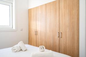 um quarto com um armário de madeira e uma cama com toalhas em Almada Cityscape Apartment em Almada