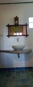 a bathroom sink with a mirror and a clock on the wall at Kuad Khon Thoe Pai Cottage in Pai