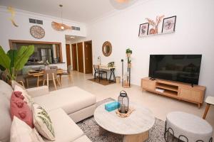 Yas Natura Bliss 1BR Apartment في أبوظبي: غرفة معيشة مع أريكة بيضاء وتلفزيون