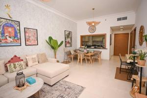 Yas Natura Bliss 1BR Apartment في أبوظبي: غرفة معيشة مع أريكة بيضاء وغرفة طعام