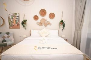 Yas Natura Bliss 1BR Apartment في أبوظبي: غرفة نوم مع سرير أبيض كبير مع قبعات على الحائط