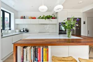 une cuisine avec des placards blancs et une table avec des livres dans l'établissement Veeve - Open Skies, à Londres