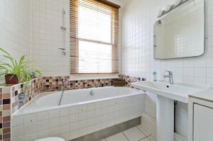 a white bathroom with a tub and a sink at Veeve - Open Skies in London
