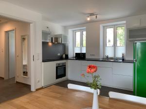 a kitchen with white cabinets and a red rose in a vase at Frundsberg-Apartment in Mindelheim