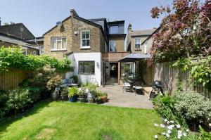 a backyard of a house with a patio and lawn at Veeve - Open Skies in London