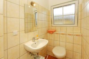 ein Bad mit einem Waschbecken, einem WC und einem Fenster in der Unterkunft Hauptstrasse 14 DHH in Ostseebad Koserow