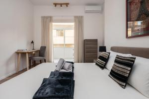 a bedroom with a large white bed and a desk at Sliema Seafront Apartment in Sliema