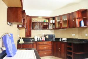 a kitchen with wooden cabinets and a black counter top at Symphony Seafront House Mombasa in Shanzu