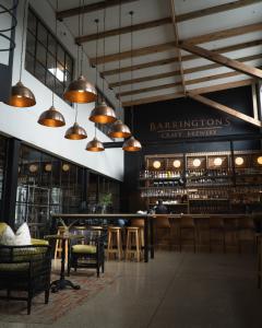 a bar with tables and chairs and pendant lights at Barrington's in Plettenberg Bay