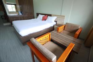 ein kleines Zimmer mit einem Bett, einem Stuhl und einer Bank in der Unterkunft Haksons Residency in Mananthavady