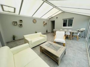 uma sala de estar com mobiliário branco e uma mesa em "VILLA DUPUY" Maison avec jardin clos arboré, 8 personnes, piscine bois privative em Talmont