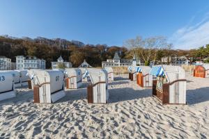 - une rangée de chaises de plage sur une plage de sable dans l'établissement Seeschloss, App 19 - direkt an der Strandpromenade, TOPLAGE, à Binz