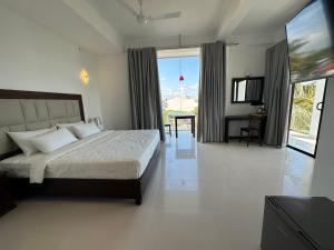 a bedroom with a bed and a large window at Mzion Hotel Weligama in Weligama