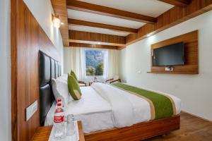 a bedroom with a large bed with a flat screen tv at Tripli Hotels Drilbu Manali in Manāli