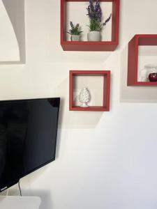 TV de pantalla plana en una pared con fotografías en Dimora dei Candelai, en Palermo