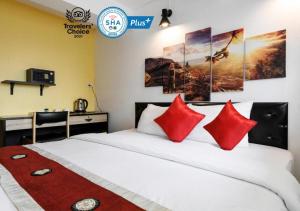 Khaosan Art Hotel - SHA Plus Certified في بانكوك: غرفة نوم مع سرير مع وسائد حمراء ومكتب