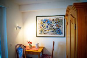 un dipinto appeso a un muro accanto a un tavolo di Hotel Malixerhof a Malix