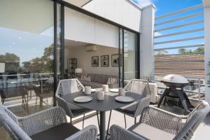a patio with a table and chairs on a balcony at Addison's Escape - A Breezy Beachfront Beauty in Shellharbour