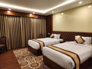 a hotel room with two beds and a chair at Paragon Hotel and Resort in Sreemangal