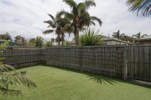 a backyard with a wooden fence and grass at Relaxed Poolside Living in a Resort-style Setting in Safety Beach
