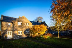 uma velha casa de tijolos com uma árvore no quintal em Acer Holiday Cottage Tideswell village Buxton Peak District by Rework Accommodation em Tideswell