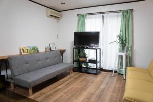ein Wohnzimmer mit einem Sofa und einem Flachbild-TV in der Unterkunft ミセスマルベリー in Utazu