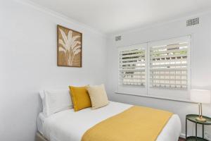 a white bedroom with a bed and two windows at Surfside Escape - A Local Lifestyle at North Beach in Gwynneville