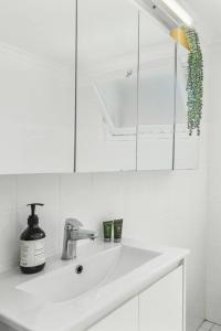 a white bathroom with a sink and a mirror at Surfside Escape - A Local Lifestyle at North Beach in Gwynneville