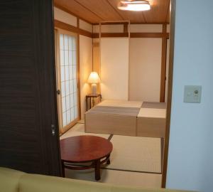 Kleines Zimmer mit 2 Betten und einem Tisch in der Unterkunft ミセスマルベリー in Utazu