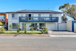 a white house with a balcony on a street at Shore Haven - A Relaxed Seaside Stay in Port Noarlunga