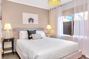 um quarto com uma grande cama branca e uma janela em Shore Haven - A Relaxed Seaside Stay em Port Noarlunga