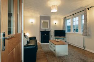 a living room with a couch and a tv at Acer Holiday Cottage Tideswell village Buxton Peak District by Rework Accommodation in Tideswell