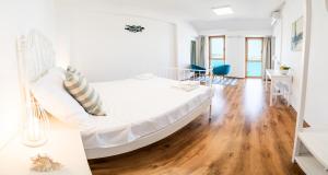 a white bedroom with a large bed and wooden floors at Umag apartment center seafront seaview old town 2 by Rentistra in Umag