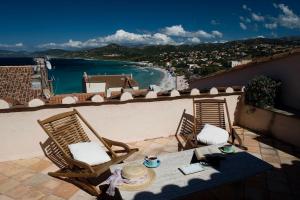 un tavolo e sedie su un balcone con vista sull'oceano di Le Maria Venezia a LʼÎle-Rousse