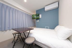 a bedroom with a bed and a table and a tv at IKEBUKURO MANGA HOUSE in Tokyo