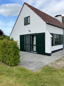 a white house with black windows and a driveway at vakantiewoning Heidehoek in Middelkerke