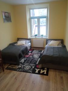Duas camas num quarto com um tapete e uma janela em Rafaelo Władycze 17/4 em Przemyśl