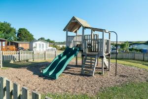 um parque infantil com um escorrega verde e uma escada em Camping Pods Trevella Holiday Park em Crantock