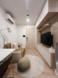 een woonkamer met een bank en een flatscreen-tv bij Prach-Chewa BKK Kaset-Nawamin in Bangkok