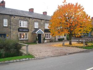a brick building with a bench and a tree at The Fairfax Arms in Gilling East