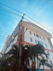 un grand bâtiment blanc avec des palmiers devant lui dans l'établissement นวนคร ออมสินอพาร์ตเมนต์ ติดห้างบิกซี Navanakorn Aomsin hotel near shopping mall,snooker and club, à Ban Lam Rua Taek