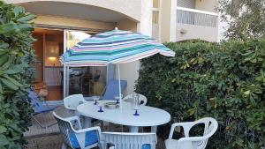 einen weißen Tisch und Stühle mit Sonnenschirm in der Unterkunft Joli studio cabine bord de mer avec piscine - 4FR503 in Saint-Cyprien