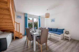 ein Esszimmer mit einem Tisch und einem blauen Sofa in der Unterkunft 400m de la plage des Sables d'Or - Maison pour 8 in Le Pointeau