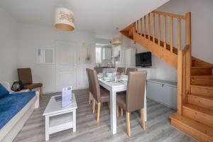 ein Esszimmer mit einem Tisch mit Stühlen und einer Treppe in der Unterkunft 400m de la plage des Sables d'Or - Maison pour 8 in Le Pointeau + 12 Fotos