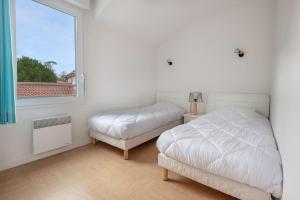 ein Schlafzimmer mit zwei Betten und einem Fenster in der Unterkunft 400m de la plage des Sables d'Or - Maison pour 8 in Le Pointeau