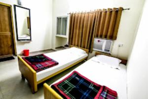 a small room with two beds and a microwave at Hotel Akashdeep, Ranchi in Rānchī