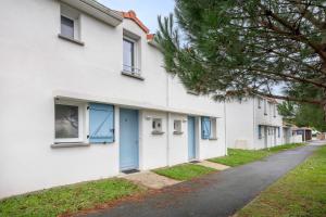 ein weißes Gebäude mit blauen Türen und einer Straße in der Unterkunft 400m de la plage des Sables d'Or - Maison pour 8 in Le Pointeau
