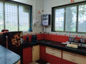 a kitchen with red cabinets and a black counter top at Darsh Bungalow....Amol Pade in Neral